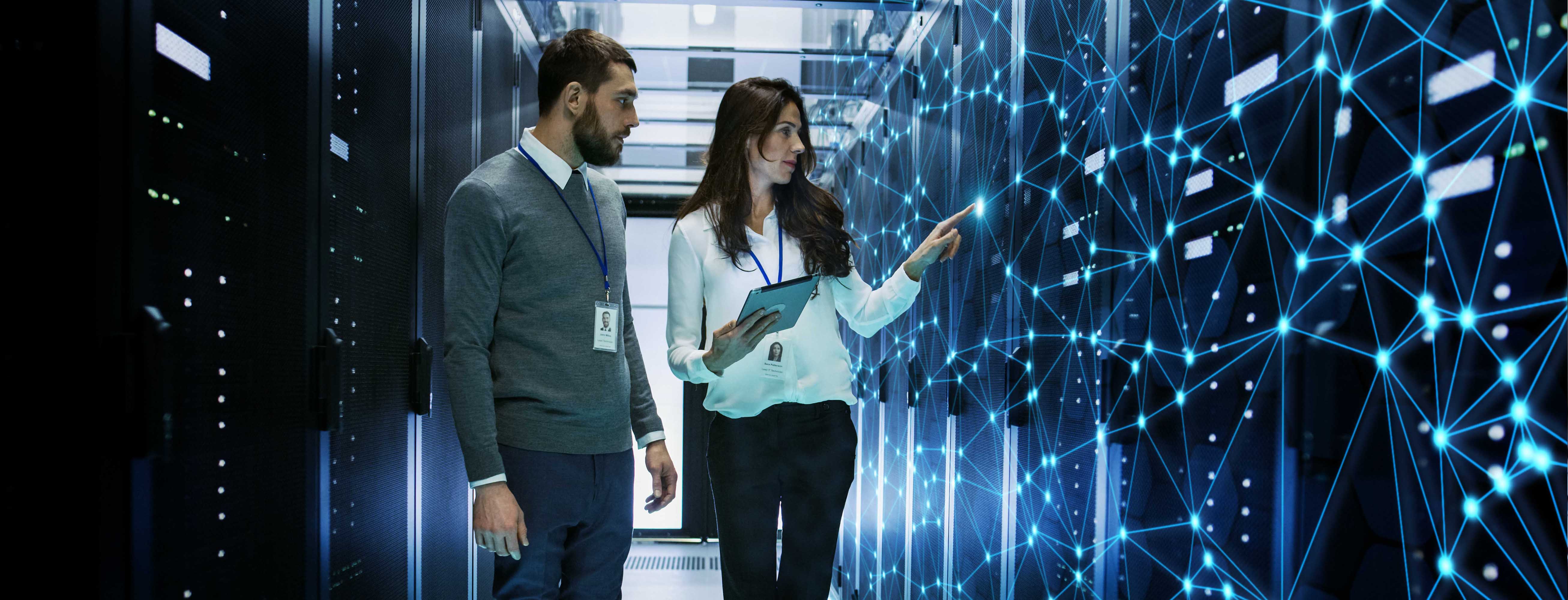 A man and a woman walking between two rows of server racks