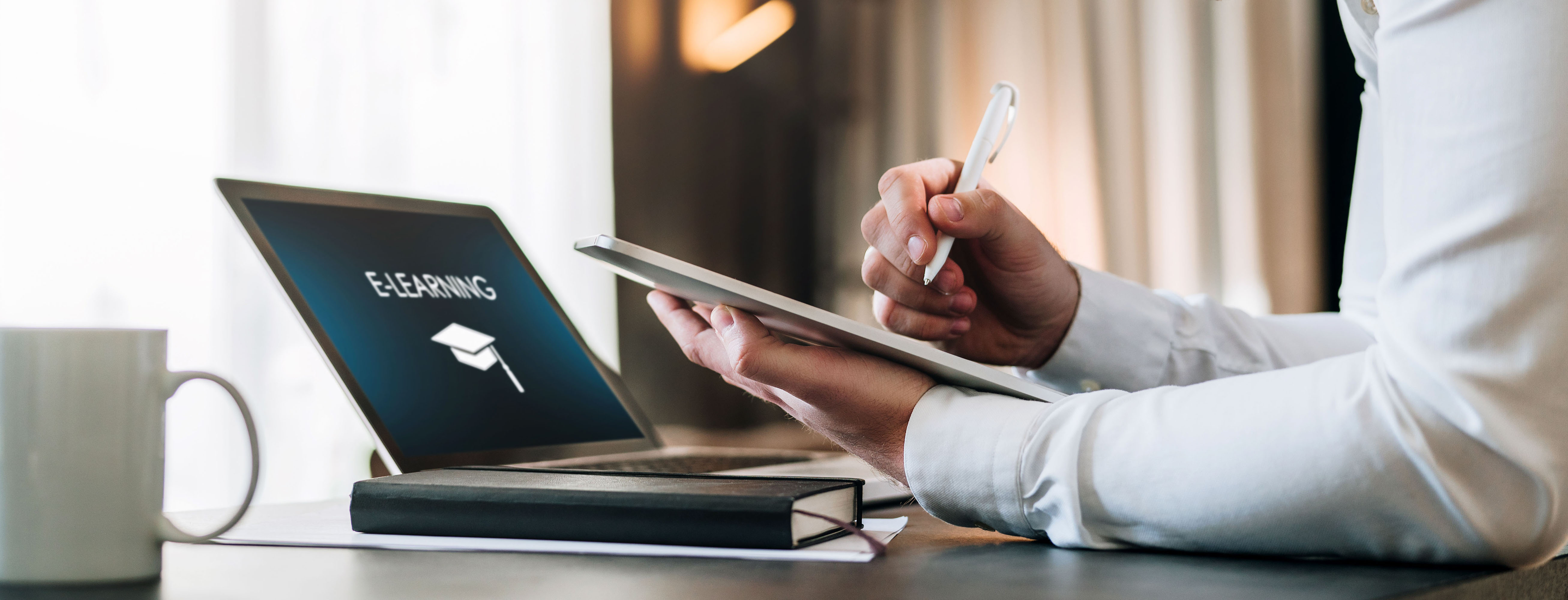 Close up image of hands, taking notes on a tablet while taking an e-learning course