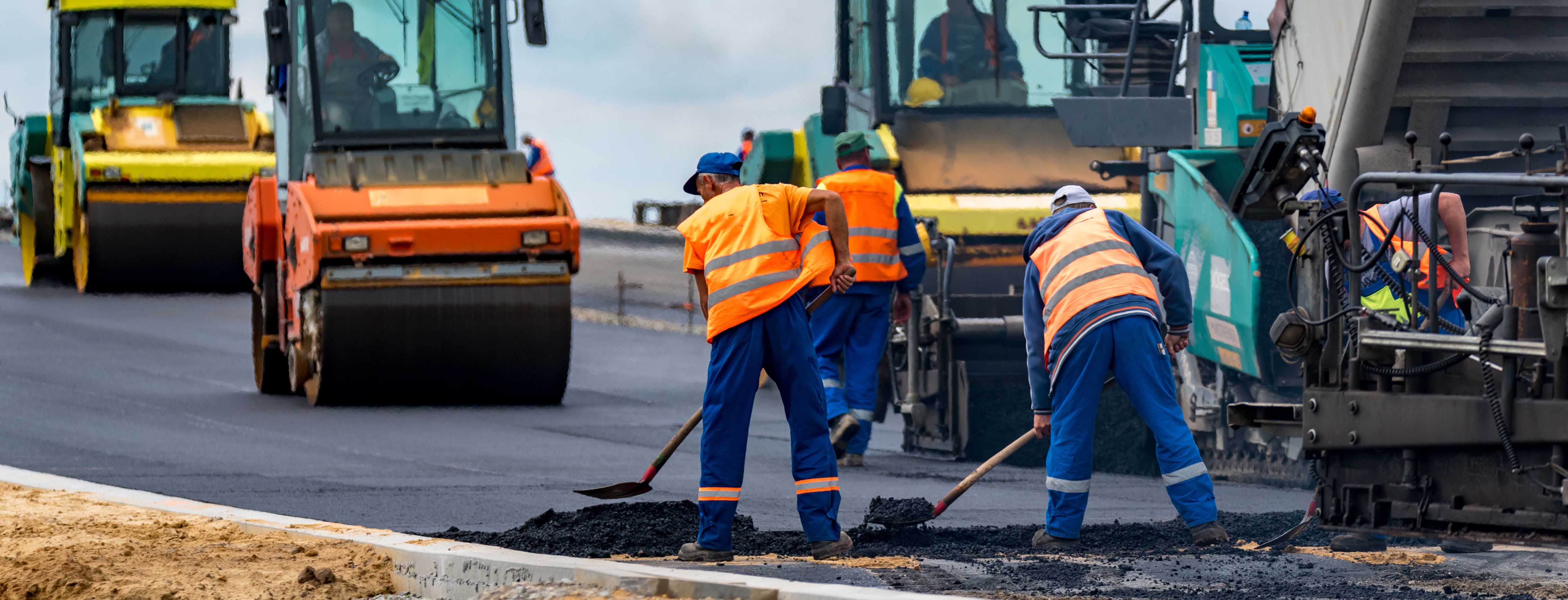 Several road workers in action. Shovelling tarmac.